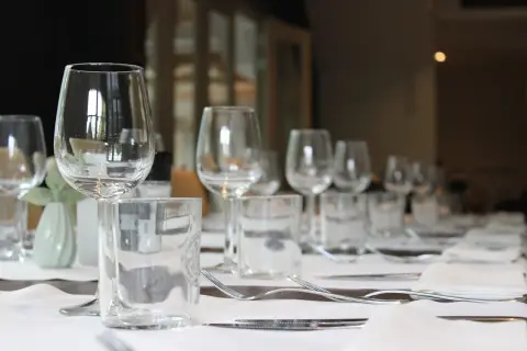 Un élégant placement verre table, prêt pour un repas. Des verres à vin et à eau, des couverts et des serviettes attendent les convives.