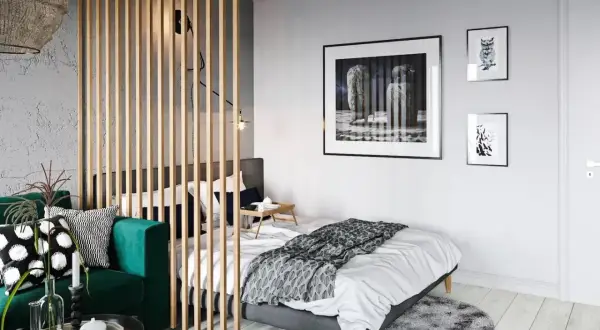 Chambre moderne séparée par un paravent en bois, avec un canapé vert et un lit.