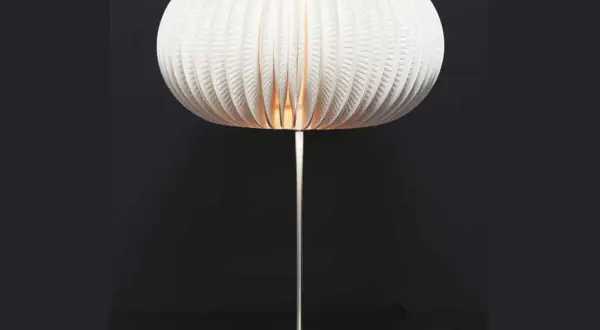 Lampe avec abat-jour sphérique en carton blanc plissé, sur pied métallique.
