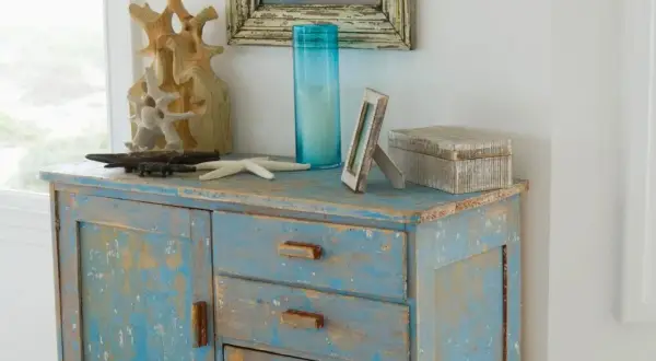 Meuble patiné bleu délavé, orné d'objets marins et d'une boîte décorative.