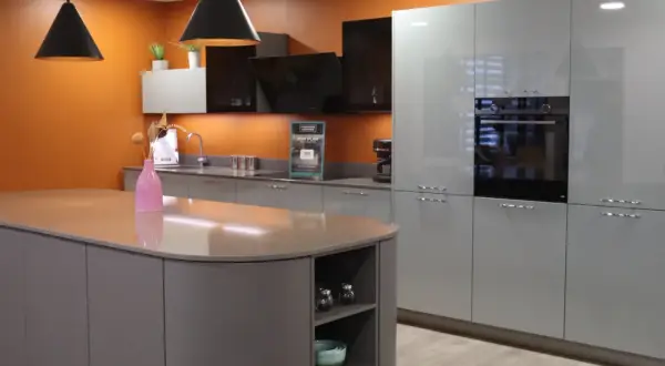 Cuisine moderne avec îlot central gris et meubles muraux bleus. Le vide sanitaire derrière le meuble cuisine est discret.