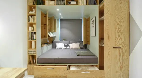 Lit intégré avec rangements et étagères en bois, décoré de coussins.