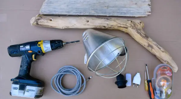 Matériel pour fabriquer une lampe en bois flotté : bois, perceuse, douille, câble, abat-jour, ampoule LED et tournevis.