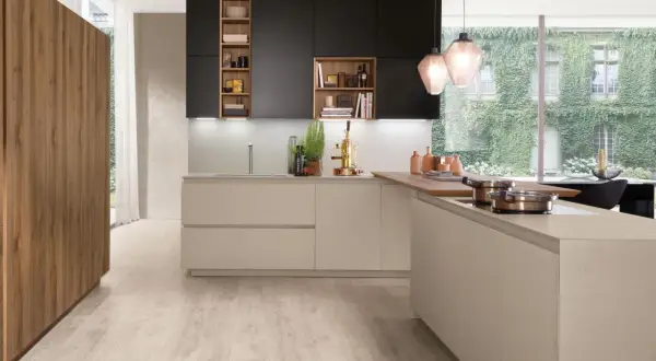 Cuisine moderne avec îlot central, armoires noires et bois, et grande fenêtre végétalisée.