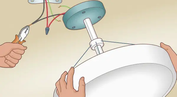Installation d'un luminaire au plafond. Un fil noir et un fil rouge sont connectés, sans fil de terre, pour le branchement luminaire 2 fils sans terre.