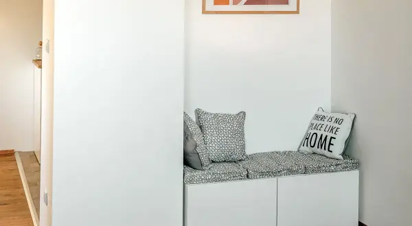 Un coin lecture zen avec un banc blanc, coussins gris et un tableau abstrait. Parfait pour se détendre.