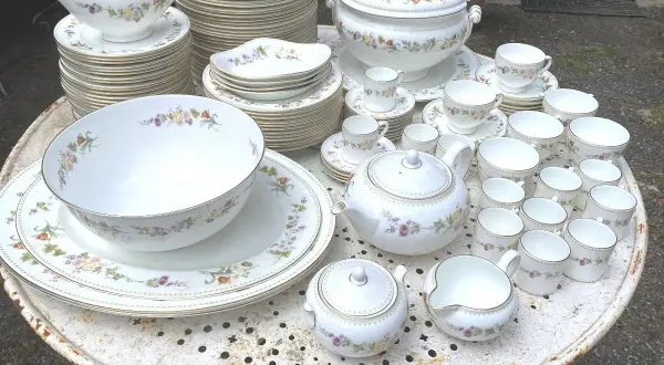 Vaste service de porcelaine à la cendre d'os, orné de délicates fleurs, comprenant théière, tasses, bols et assiettes.