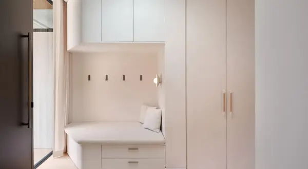 Banquette intégrée avec rangements sous pente, murs clairs, parquet bois.
