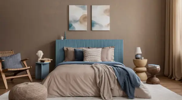 Une peinture chambre adulte 2 couleurs, avec un lit douillet, un fauteuil en rotin et des tableaux abstraits.