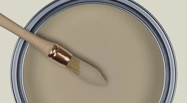 Pinceau trempé dans une peinture beige grège, prêt à transformer un espace.
