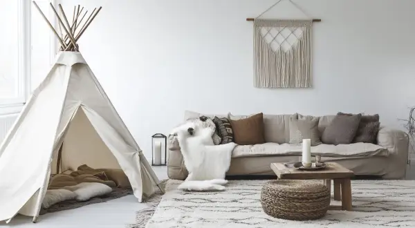 Un coin jeux enfant salon avec une tente tipi, coussins douillets et un tapis douillet.