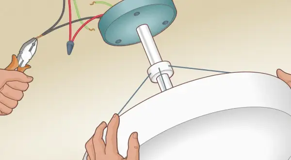 Installation d'un ventilateur de plafond : branchement domino 3 fils et 2 fils. Mains tenant le luminaire et pinces pour les fils électriques.