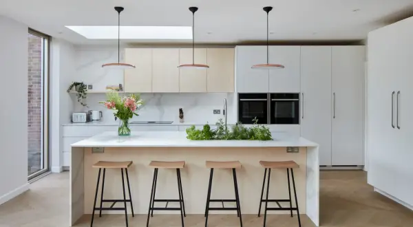Une cuisine moderne et lumineuse, parfaite pour imaginer sa cuisine de rêve. Îlot central avec tabourets, armoires épurées et plantes aromatiques.