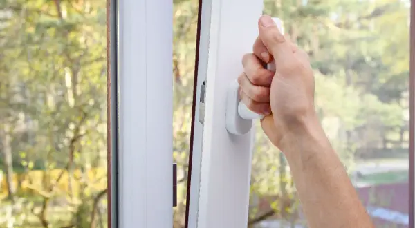 Main tenant ouvrant une fenêtre pour comment purifier l'air de sa maison. L'air frais extérieur entre, apportant la nature.