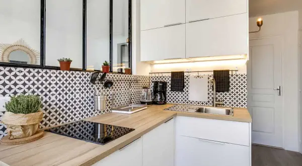 Coin cuisine moderne avec plan de travail en bois, carrelage graphique noir et blanc, et électroménager.