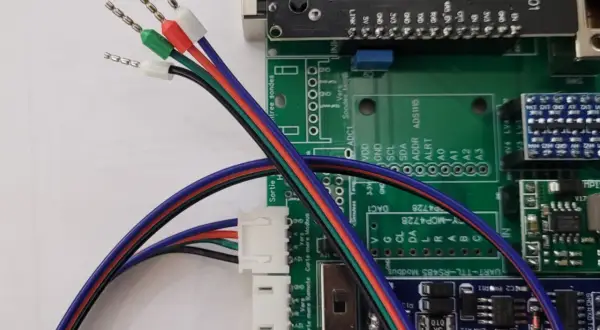 Fils multicolores, dont un fil noir et blanc 12V, connectés à une carte électronique.