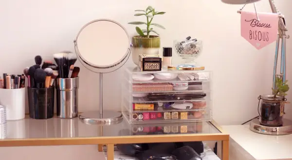 Coiffeuse organisée avec miroir, pinceaux, maquillage et plante.
