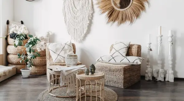 Salon au thème bohème chic avec fauteuils en rotin, coussins graphiques, macramé mural et bougeoirs sculptés.