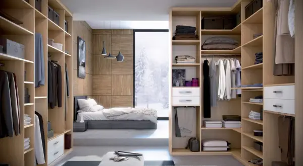 Un dressing fermé bien organisé, avec des étagères en bois clair, des vêtements suspendus et pliés, et une vue sur un paysage hivernal.