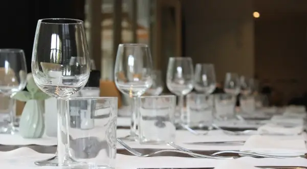 Un élégant placement verre table, prêt pour un repas. Des verres à vin et à eau, des couverts et des serviettes attendent les convives.