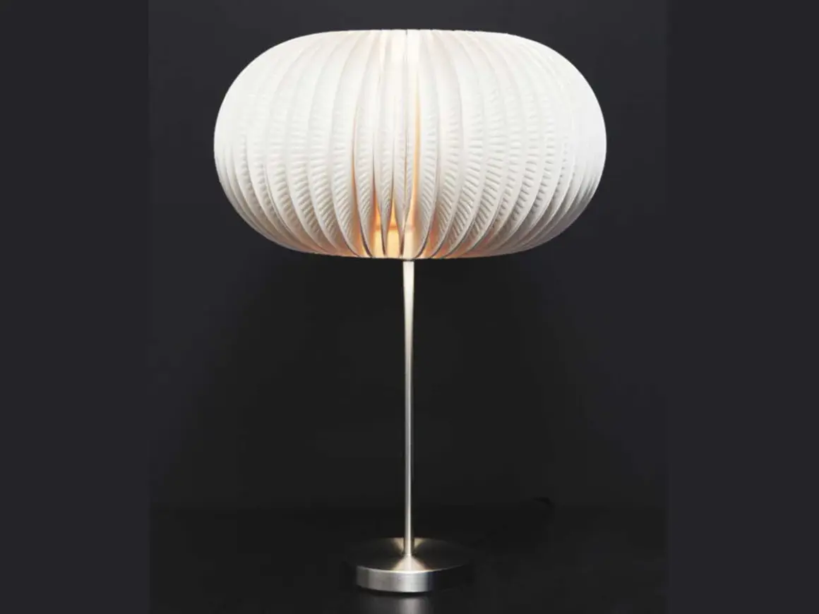 Lampe avec abat-jour sphérique en carton blanc plissé, sur pied métallique.