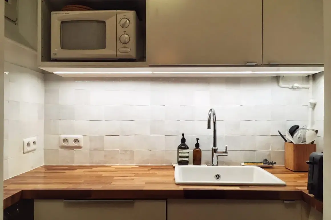 Cuisine blanche épurée avec crédence en zellige texturé, plan de travail en bois, évier et robinetterie modernes.