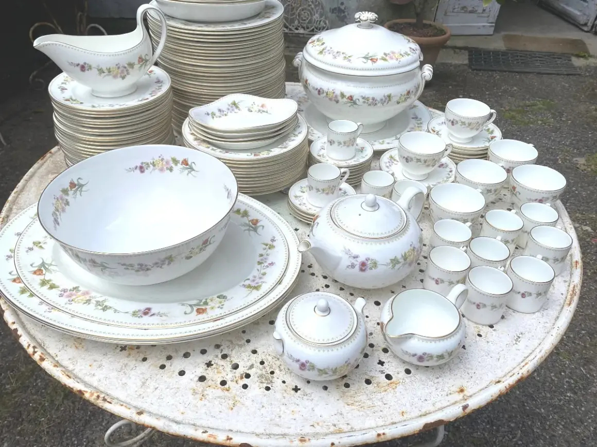 Vaste service de porcelaine à la cendre d'os, orné de délicates fleurs, comprenant théière, tasses, bols et assiettes.