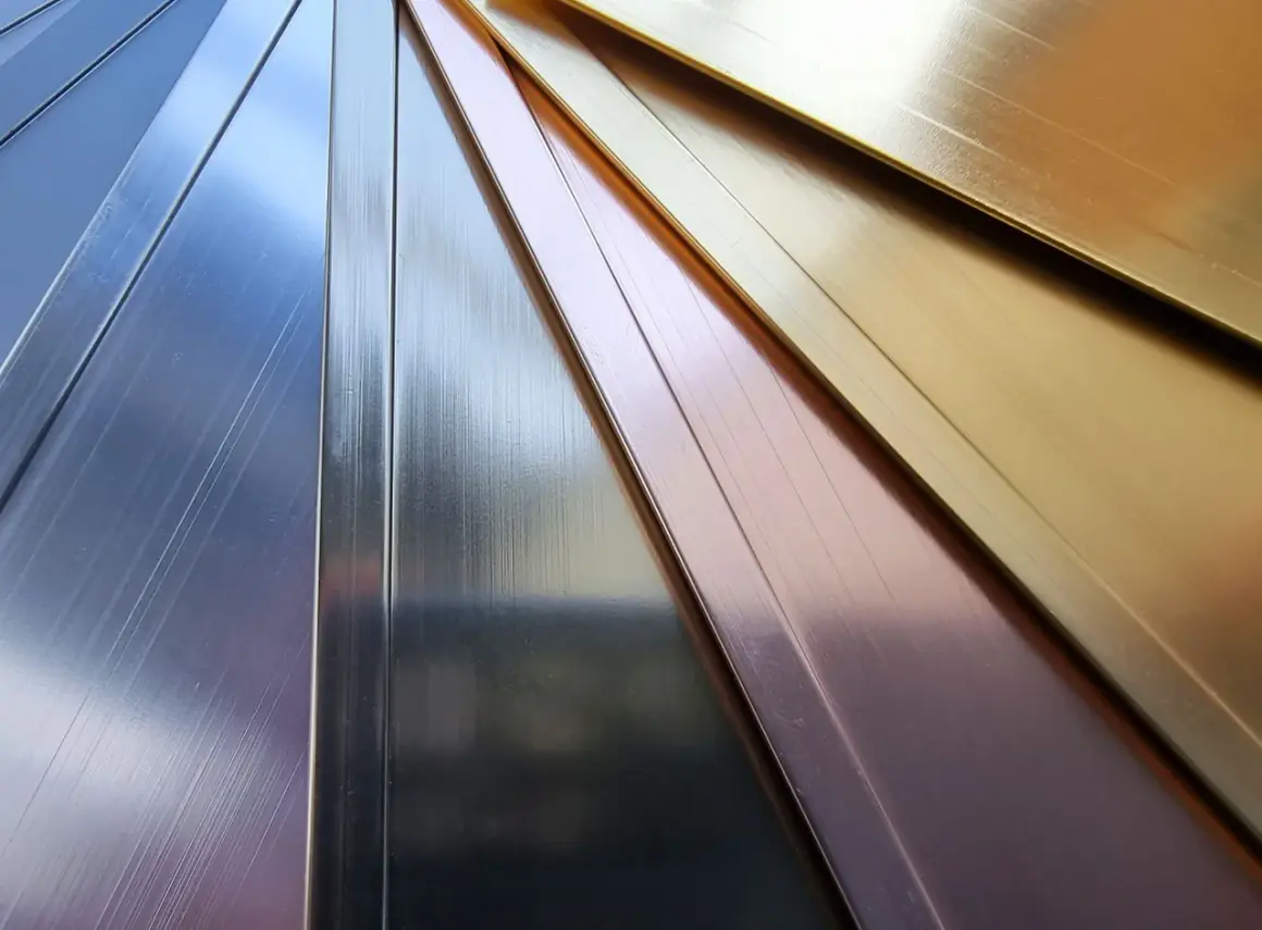 Échantillons de métaux aux reflets variés : argent, cuivre, or. La couleur des métaux est mise en valeur par la lumière.