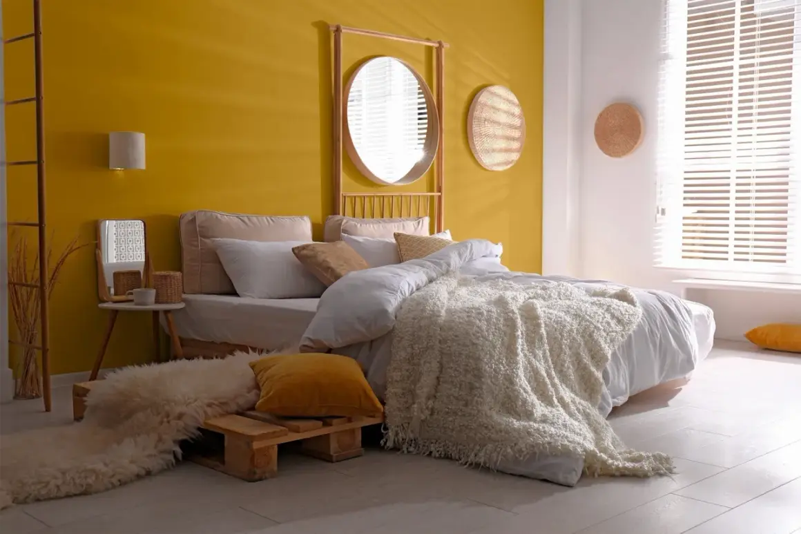 Chambre de fille avec mur jaune, lit blanc, tapis shaggy et miroir rond.