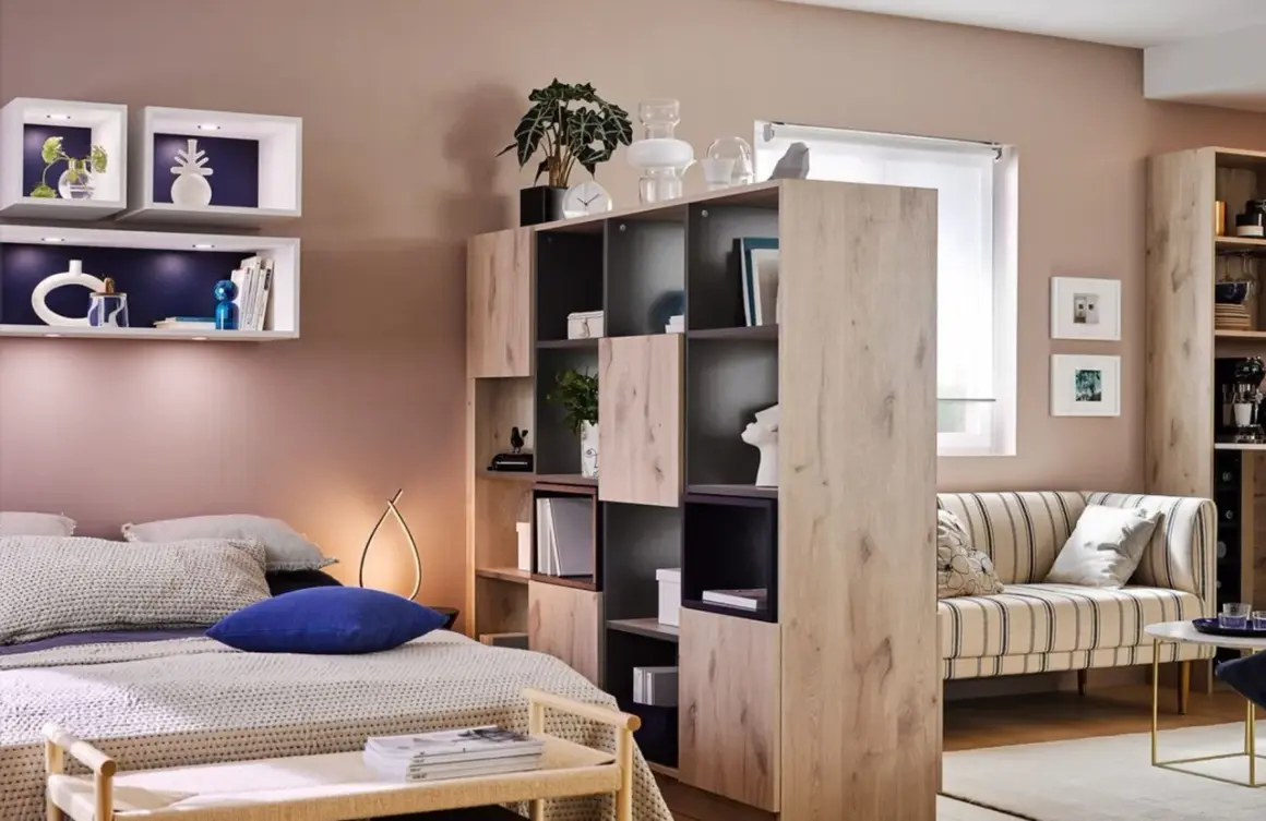 Chambre et salon séparés par une étagère modulable, avec lit douillet et canapé rayé.