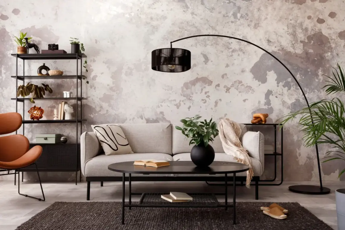 Salon au **couleur mur style industriel**, avec canapé gris, fauteuil orange, étagères noires et table basse.