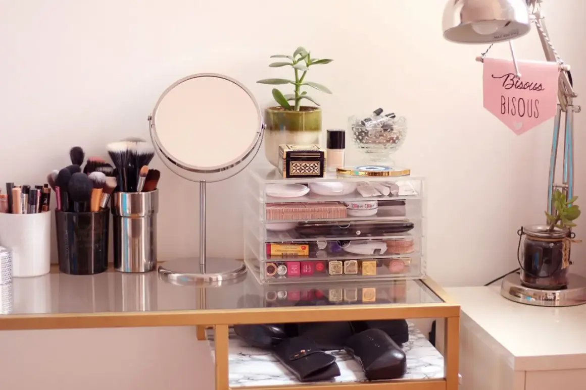 Coiffeuse organisée avec miroir, pinceaux, maquillage et plante.