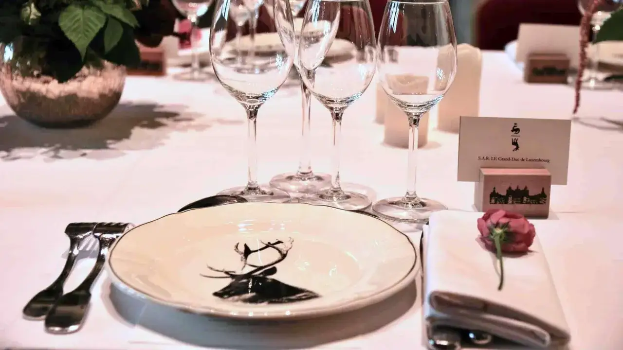 Un élégant placement verre table avec une assiette cerf, des couverts, une rose et une carte nominative pour le Grand-Duc de Luxembourg.