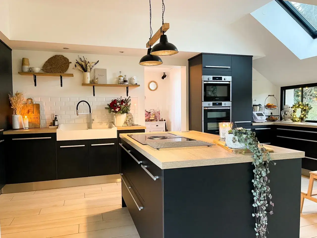 Cuisine moderne avec un îlot central doté d'une plaque de cuisson intégrée, des armoires noires et un évier blanc.