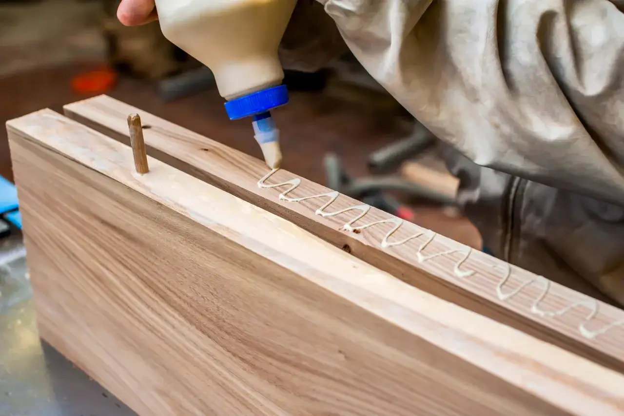 Application de colle &agrave; bois sur des pi&egrave;ces de bois pour un assemblage solide.