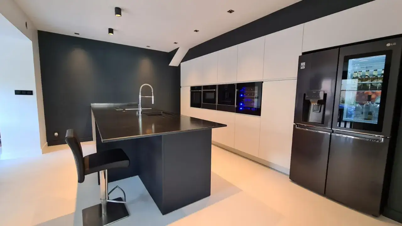 Une cuisine moderne et épurée, parfaite pour imaginer sa cuisine idéale : îlot central noir, électroménagers intégrés et réfrigérateur LG.