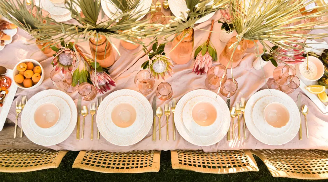 Un magnifique ensemble de vaisselle aux motifs géométriques, avec des assiettes, des bols et des couverts dorés, prêt pour un repas en plein air.