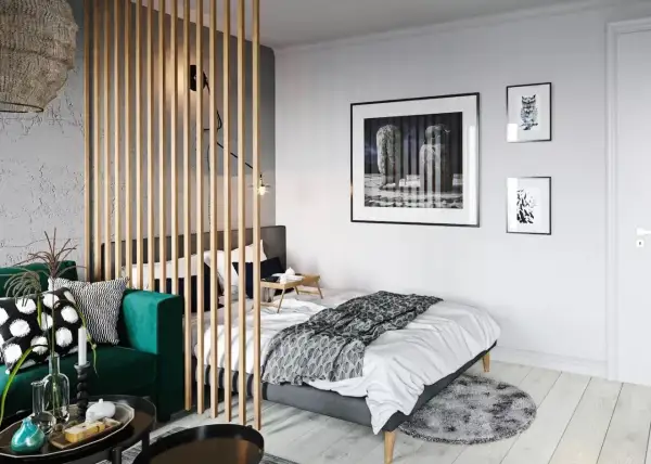 Chambre moderne séparée par un paravent en bois, avec un canapé vert et un lit.