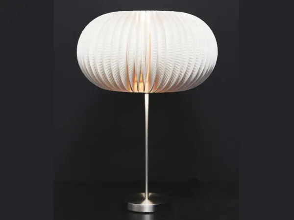 Lampe avec abat-jour sphérique en carton blanc plissé, sur pied métallique.