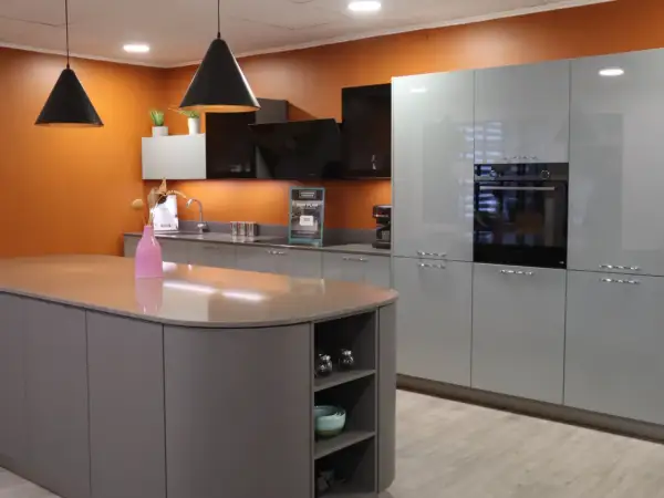 Cuisine moderne avec îlot central gris et meubles muraux bleus. Le vide sanitaire derrière le meuble cuisine est discret.