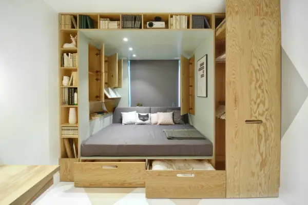 Lit intégré avec rangements et étagères en bois, décoré de coussins.
