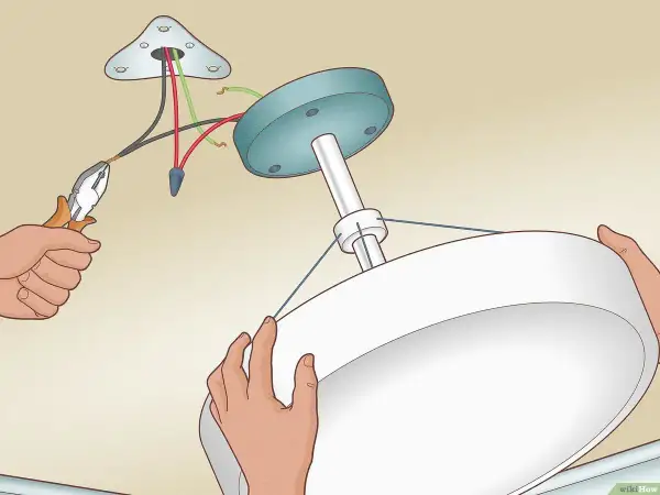 Installation d'un luminaire au plafond. Un fil noir et un fil rouge sont connectés, sans fil de terre, pour le branchement luminaire 2 fils sans terre.