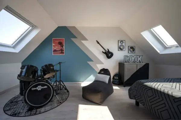 Chambre d'ado avec batterie, guitare électrique, pouf et lit décoré.