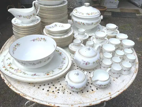 Vaste service de porcelaine à la cendre d'os, orné de délicates fleurs, comprenant théière, tasses, bols et assiettes.