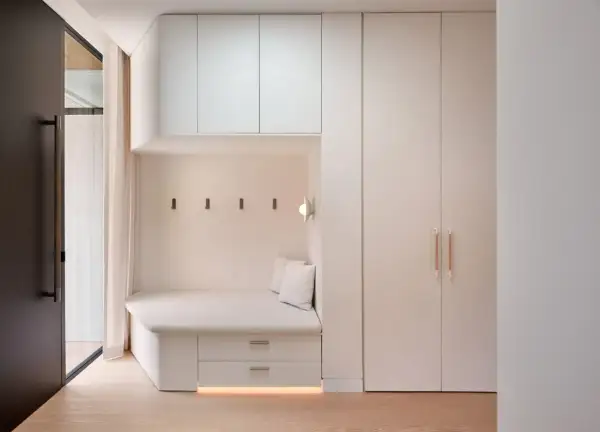 Banquette intégrée avec rangements sous pente, murs clairs, parquet bois.