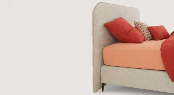 Tête de lit beige avec coussins rouges et orange.