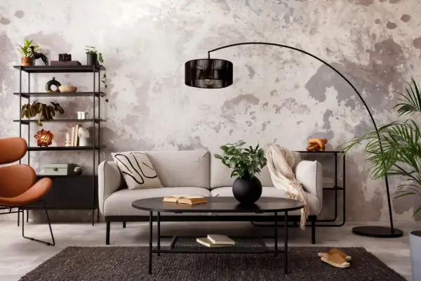Salon au **couleur mur style industriel**, avec canapé gris, fauteuil orange, étagères noires et table basse.