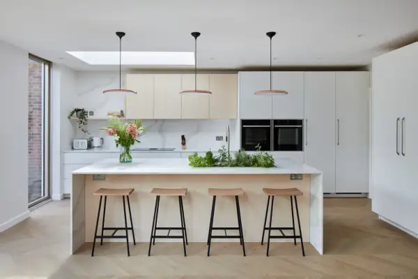 Une cuisine moderne et lumineuse, parfaite pour imaginer sa cuisine de rêve. Îlot central avec tabourets, armoires épurées et plantes aromatiques.