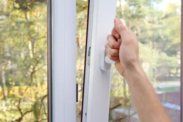 Main tenant ouvrant une fenêtre pour comment purifier l'air de sa maison. L'air frais extérieur entre, apportant la nature.