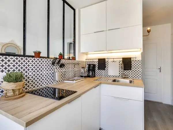 Coin cuisine moderne avec plan de travail en bois, carrelage graphique noir et blanc, et électroménager.
